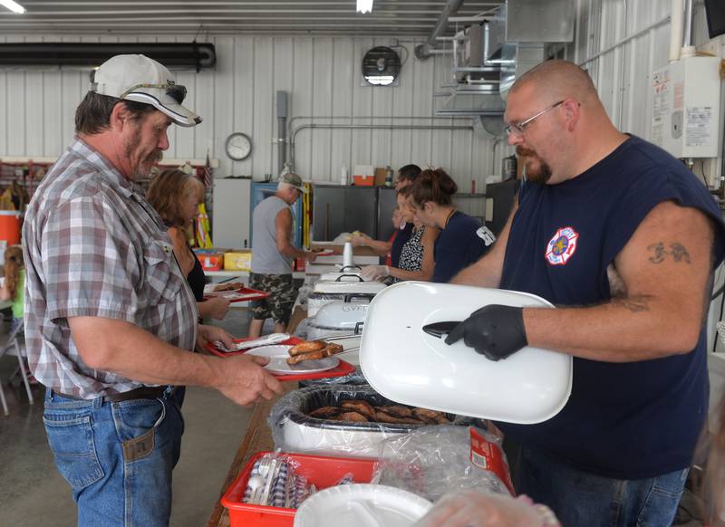 German Valley Firefighter Josh Roach serves two pork chops to a customer during the fire department's pork chop dinner on Saturday, July 15, 2023 during German Valley Days.