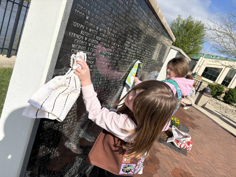 Local Girl Scouts Ryleigh Johnston and Alexa Johnston dry off one of the walls Saturday, April 25, at the Middle East Conflicts Wall Memorial in Marseilles.