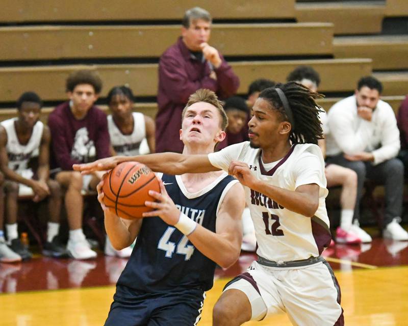 Morton East's Donvan Johnson (12) blocks the shot of Downers Grove South's Justin Sveiteris (44) during the first quarter on Saturday Dec. 9, 2023, held at Morton East High School.