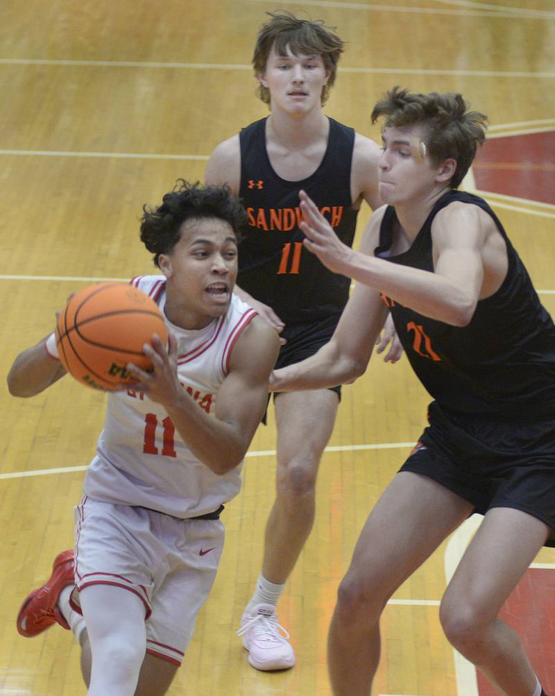 Ottawa’s Hezekiah Joachim drives to the basket past Sandwich’s Nick Michalek and EJ Treptow in the 1st period Tuesday at Ottawa.