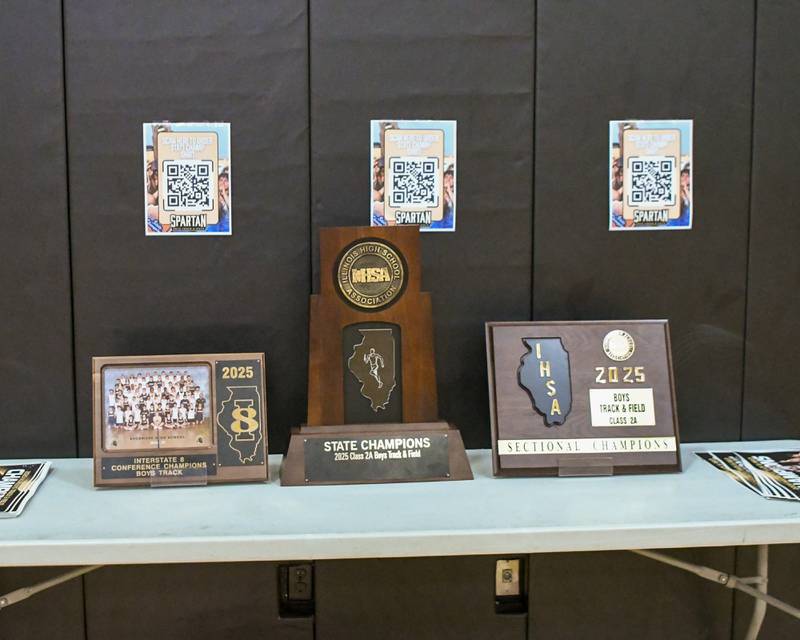 The IHSA State Champions trophy along with the sectional champion plaque and team photo sit on a table during the pep rally on Wednesday June 4, 2025, at Sycamore High School after the Sycamore High School boys track team won the 2A state title.