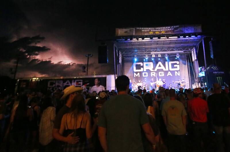 Lighting illuminates through storm clouds off in the distance behind the stage as Craig Morgan sings during the 102nd Marshall-Putnam Fair on Thursday, July 13, 2023 in Henry.