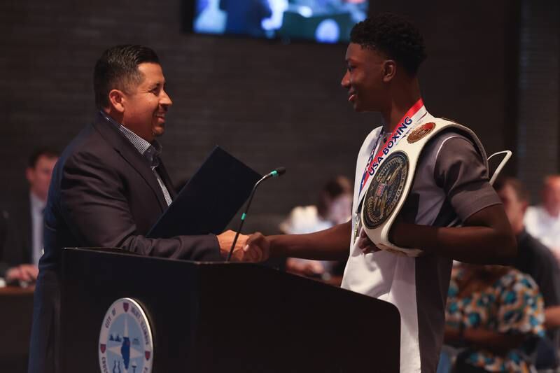 Councilman Cesar Cardenas presents a proclamation by the City of Joliet to Joseph “JoJo” Awinongya Jr, 4 time Junior Olympics Champion and Joliet native, at the Joliet City Council meeting on Tuesday, July 18th, 2023.