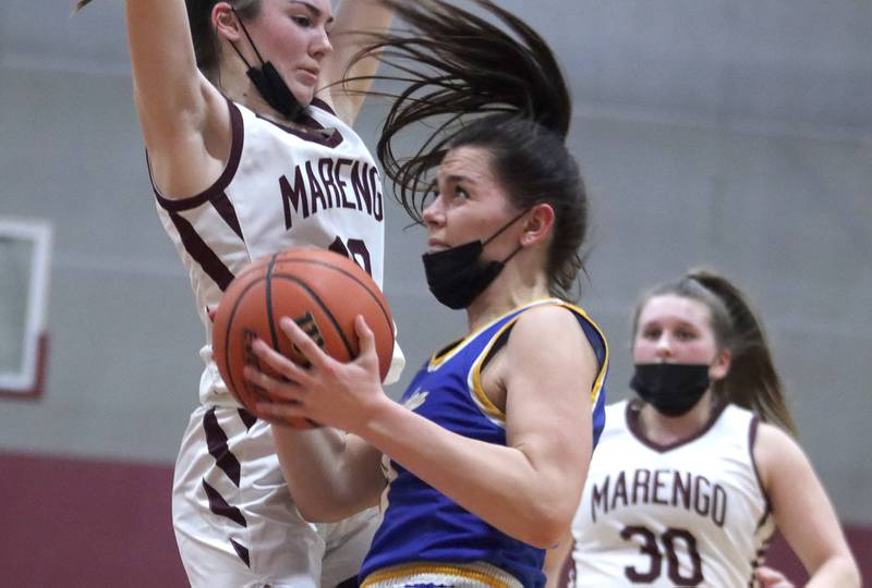 Marengo’s Bella Frohling, left, defends as Johnsburg’s Macy Madsen looks for the hoop during girls varsity basketball action in Marengo Thursday night.