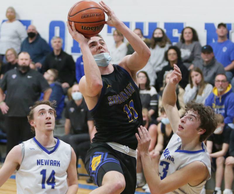 Somonauk's Alex Krejci, (11) runs into the laneto score a basket between Newark defenders Grandon Mitchell, (14) and teammate Mitchell Kruser, (3) on Tuesday, Feb. 15, 2022 in Newark.