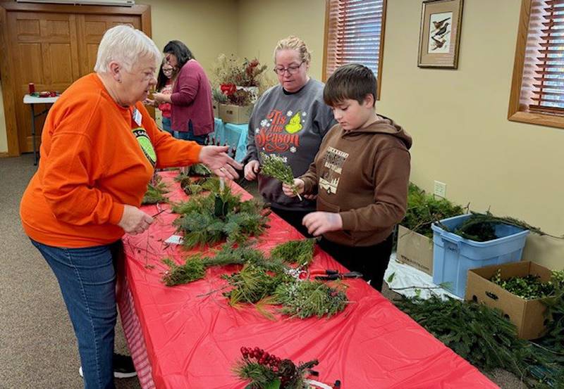 Master Gardener, Barb Dalbach, helps 4-H’er Joey Vinyard create his centerpiece.