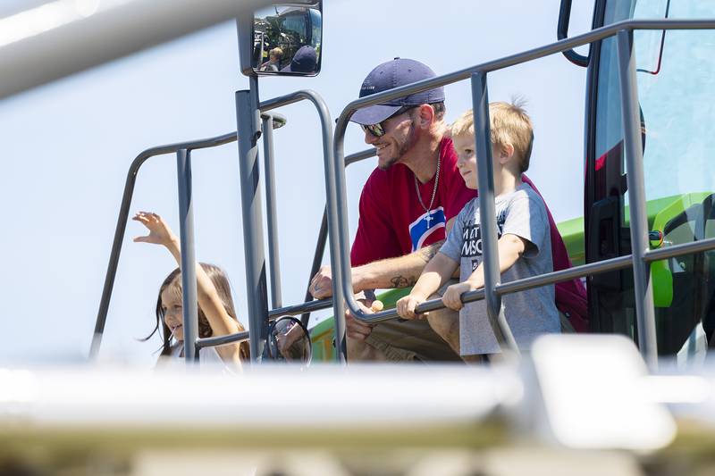 Flanked by kids Tianna, 6, and TJ, 3, Travis Shroyer of Dixon has a family picture taken Saturday, June 28, 2025, on top of a farming sprayer at Rock Falls' Touch-a-Truck event.