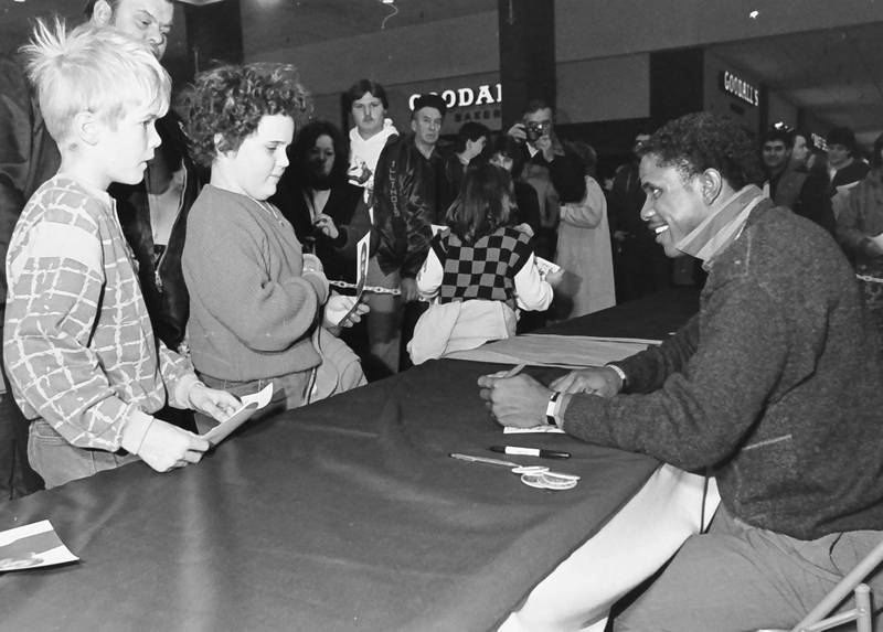 Dennis McKinnon, (right) former Chicago Bears player and Super Bowl champion signs autographs to children at the Peru Mall in 1986.