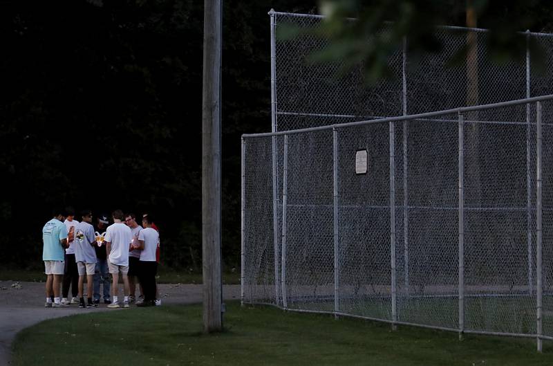 Friends of Riely Teuerle have a private moment near the baseball field that Teuerle played on when he was a child during a candlelight celebration for Teuerle on Thursday, August 11, 2022, at Towne Park, 100 Jefferson Street in Algonquin. Teuerle was killed in a car crash in Lake in the Hills on Tuesday. Over 100 family members and friends gathered at the park to remember and celebrate Teuerle’s life.