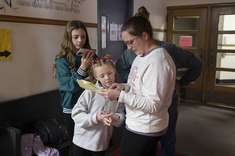 Laura Sharp shows items she put in the time capsule to her kids Claire (left), 11, and Grace, 7, Monday, Dec. 23, 2024. Sharp was an assistant teacher at Lincoln School when the capsule was filled.