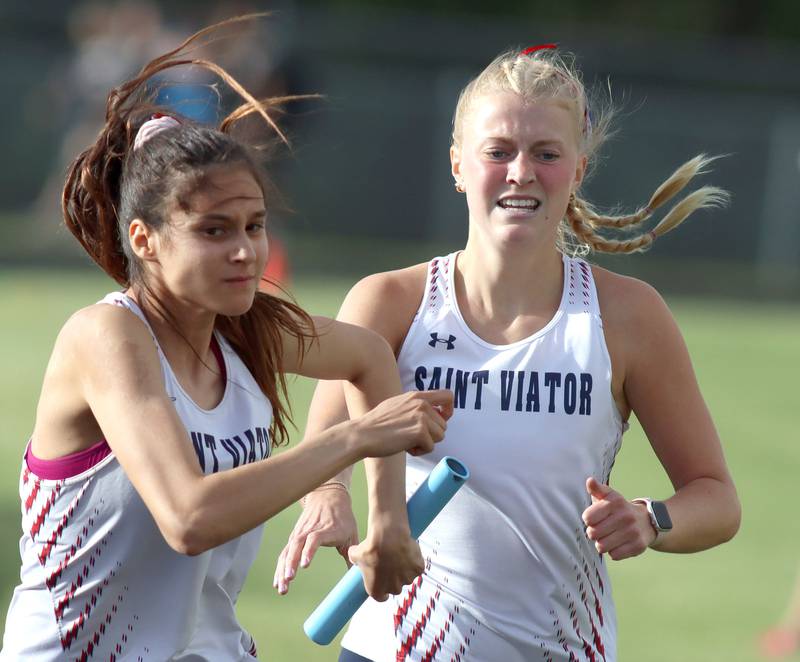 St. Viator’s Allie Long, right, hands off to Jada Baer in the 3200-meter relay in IHSA Class 2A Girls Sectional Track action at Genoa-Kingston School in Genoa on Friday, May 16, 2025.