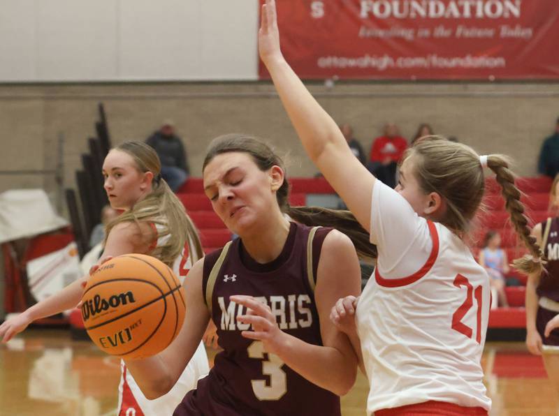Morris's Lily Hansen fights her way in the lane as Ottawa's Hailey Thrush guards her on Tuesday, Dec. 9, 2025 in Kingman Gymnasium at Ottawa High School.