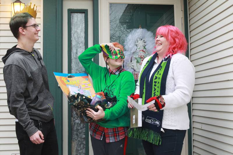 Jennifer Coble (on right) stands next to her children, Taylor, 16, and Aubrey 15, in front of their home as  they have fun showing off what is in a basket of presents for a family in the neighborhood who they are about elf in Round Lake Beach.