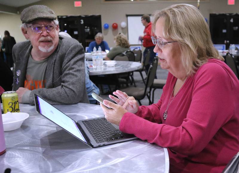 Randi Olson, Democratic candidate in the 70th District state representative race, keeps updated by phone and computer as DeKalb County Board candidate Stewart Ogilvie looks on Tuesday, Nov. 5, 2024, at the election night watch party at River Heights Golf Club in DeKalb.