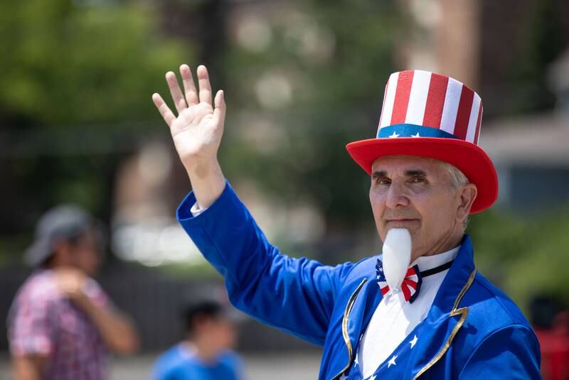 A parade member dressed as Uncle Sam waves to the audience during the Downers Grove Independence Day Parade on Main Street in Downers Grove on Tuesday, July 4, 2023.