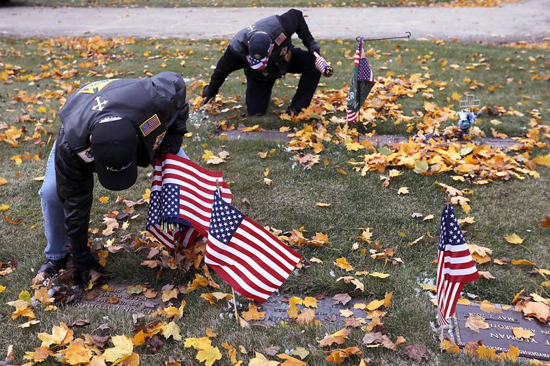 Mark Kuczera and Brain Quart place flags during the Veterans Day flag placement ceremony Tuesday, Nov. 11, 2025, at the gravesites of veterans at McHenry County Memorial Park Cemetery in Woodstock. Members of the Knights of Columbus Patriotic 4th Degree from the Bishop Boylan Assembly placed American Flags at nearly 140 veterans' grave markers.
