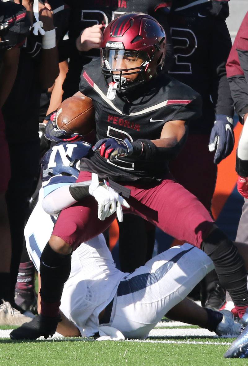 Peoria's TQ Webb tries to break free from Nazareth's James Penley during their IHSA Class 5A state championship game Saturday, Nov. 26, 2022, in Memorial Stadium at the University of Illinois in Champaign.