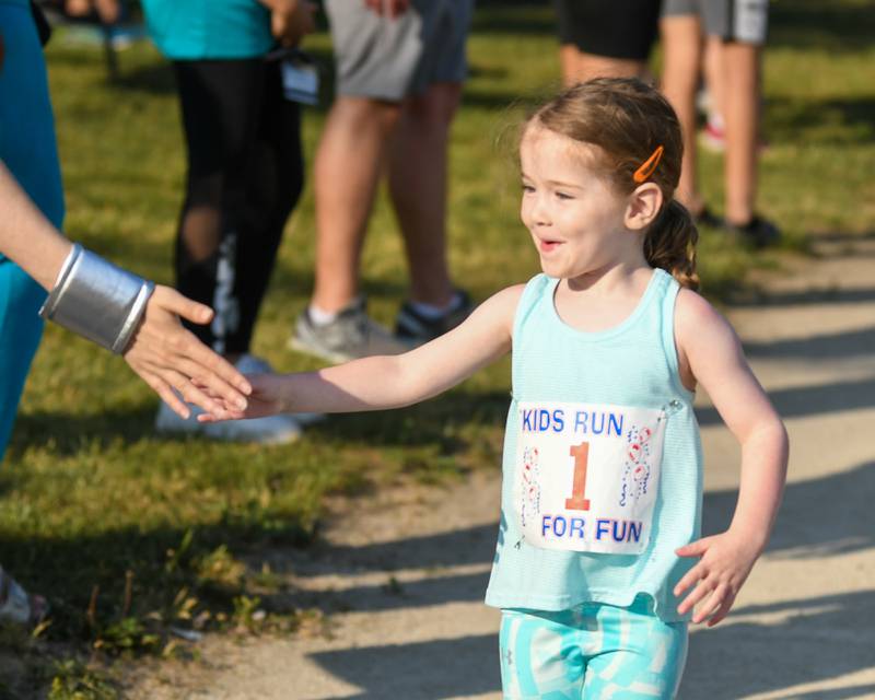 Eloise Doster, 4 years old, of La Granges gets high fives from Wonder Woman as she crosses the finish line of the 1 lap race during the Leadershop event held in La Grange on Friday June 9, 2023.