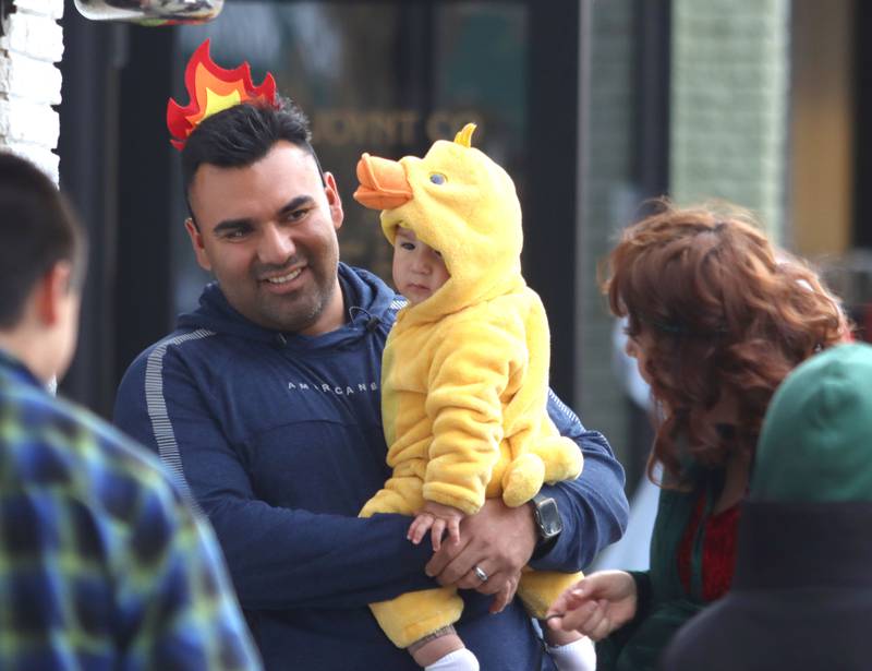 Jose Garcia of Crystal Lake trick-or-treats with his ten-month-old son Ezekiel and wife Jazmin in downtown Crystal Lake on Friday, October. 31, 2025
