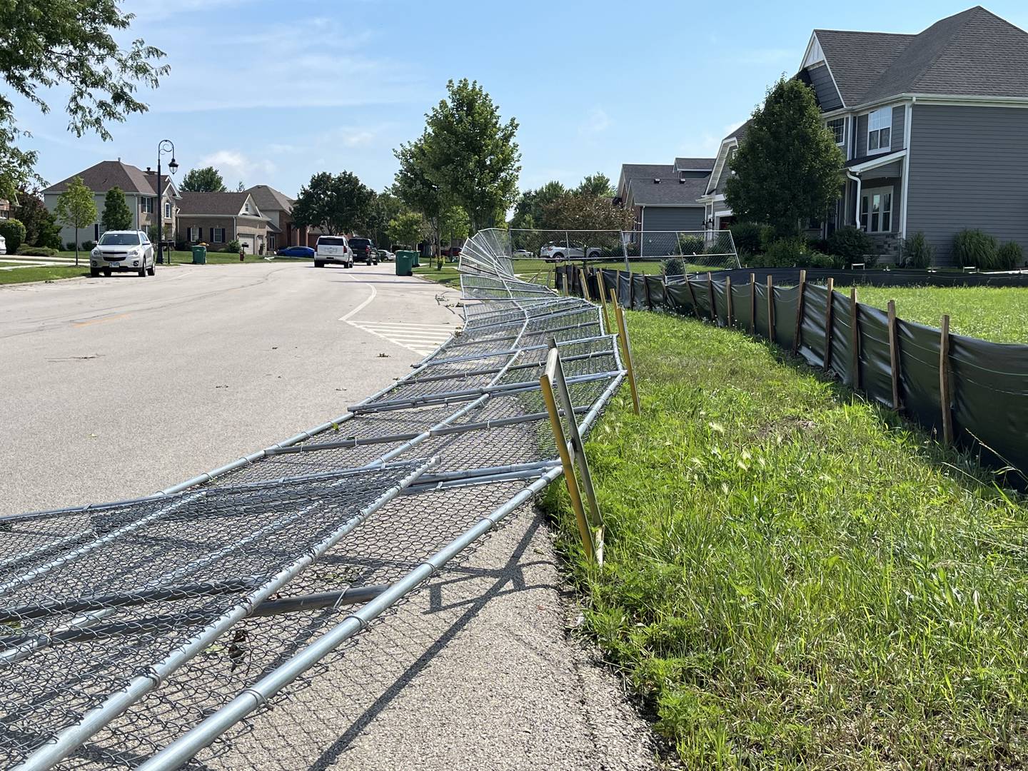 A metal fence lies twisted on the ground in the River Crossing subdivision in Shorewood on Tuesday, July 16, 2024.  Severe storms producing tornadoes and heavy rains swept through Will County on Monday night.