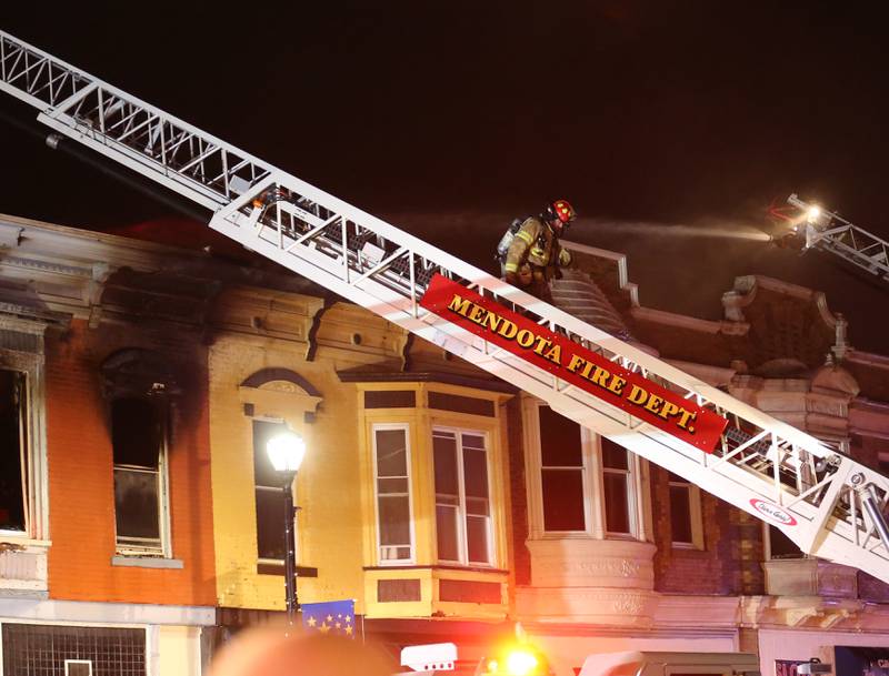 A firefighter climbs down a Mendota ladder truck while fighting a fire at 708 Illinois Avenue on Friday, Dec. 30, 2022 downtown Mendota.