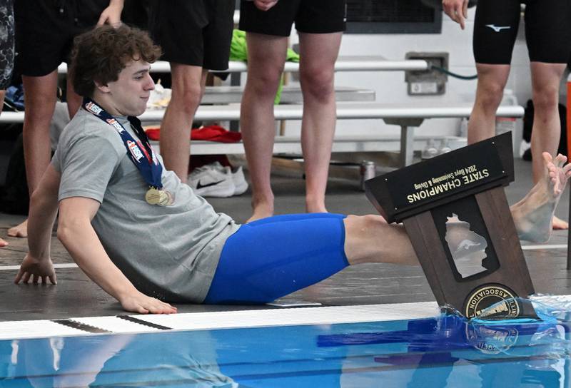 On his first attempt, Hinsdale Central’s Brody Marcet slips and falls on the pool deck and the state championship trophy falls into the water at the conclusion of the boys state swimming and diving finals at FMC Natatorium on Saturday, Feb. 24, 2024 in Westmont. He was not injured and he succeeded on the second try.