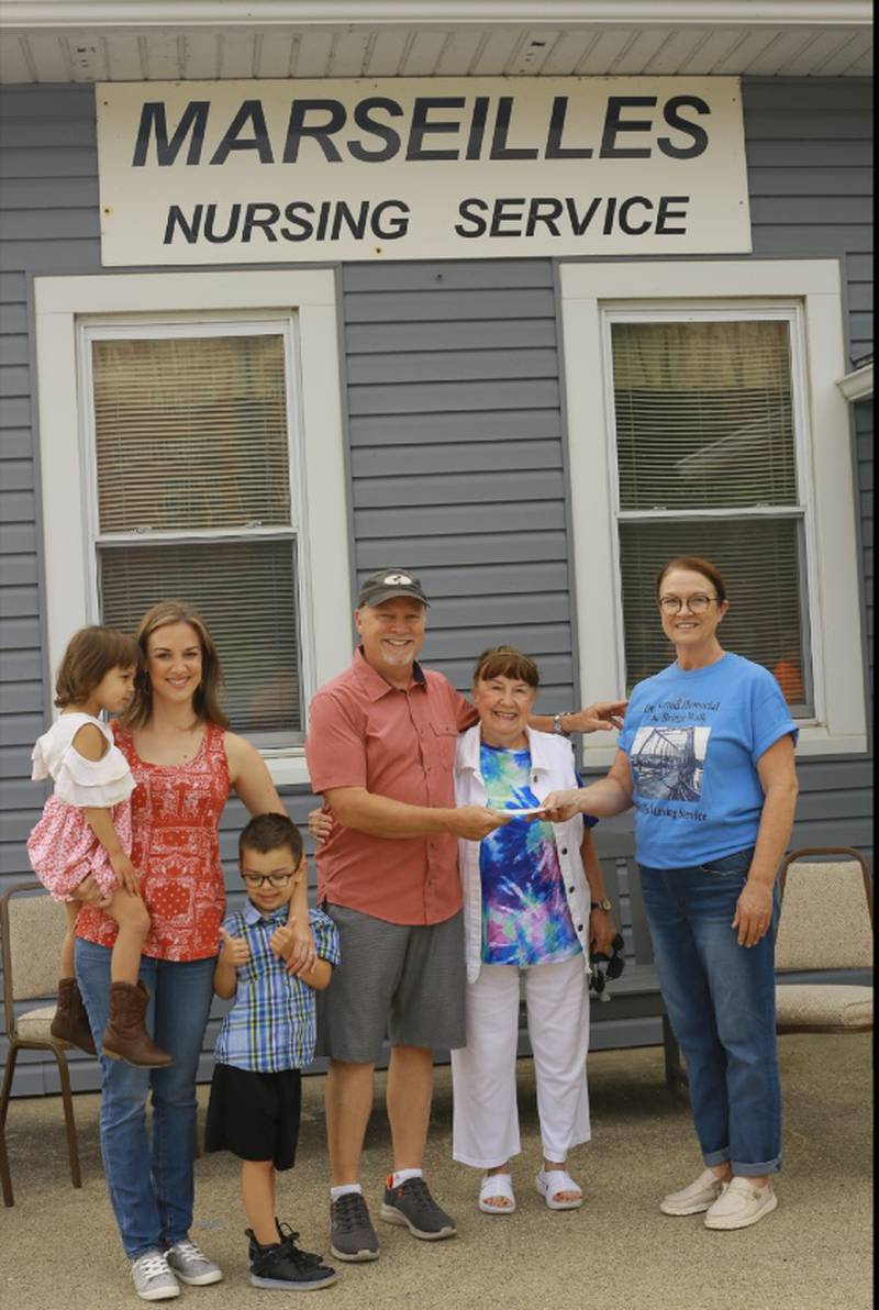 Presenting a $10,000 donation for the Marseilles Nursing Service to Kathy Rosengren, RN, is Dr. Sutton’s son, Peter Sutton, who is visiting from San Jose, California; Peter’s daughter (left), Alyssa, along with her children and Seattle Sutton (second from right).