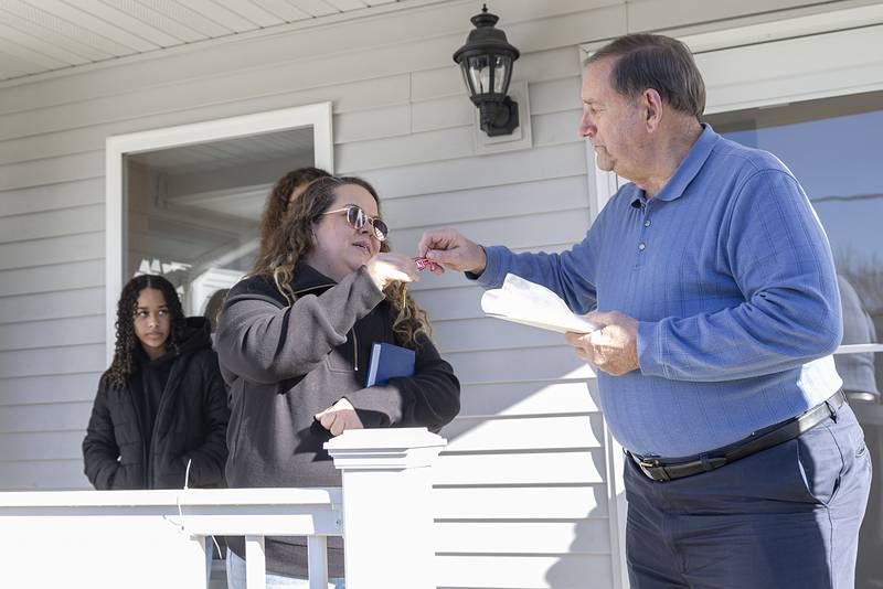 Bob Gingras, Dixon Habitat for Humanity construction committee chairperson, hands over the keys to newest homeowner Nichole Richardt Sunday, Nov. 23, 2025. Richardt will share the home with her children Isaiah Chattic, Azareya Chattic, and Devrin Thomas.