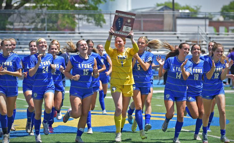 Goalkeeper Anna Bigenwald carries the championship plaque aloft as the Lyons Township girls soccer team rushes to their fans after their 2-0 overtime win over Downers Grove North in the Class 3A Lyons Regional final on May 23, 2026 at Lyons Township High School in LaGrange.
