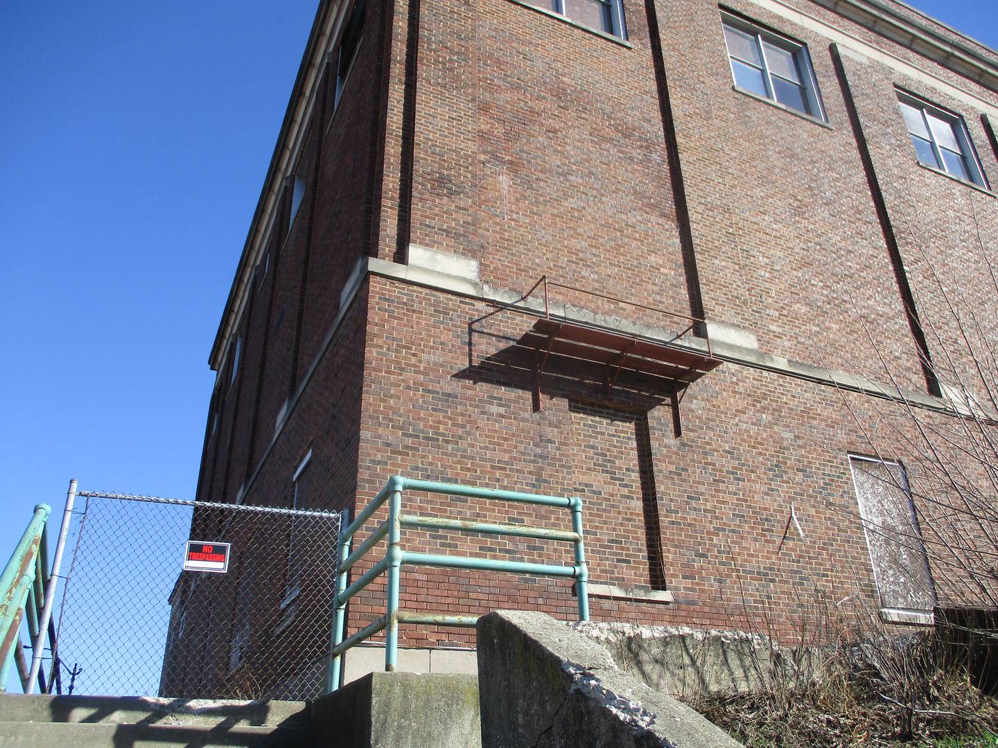 .A fence blocks entry to a sidewalk that runs alongside the section of the former Joliet Catholic High School building that housed a gym and cafeteria. Feb. 29, 2024.