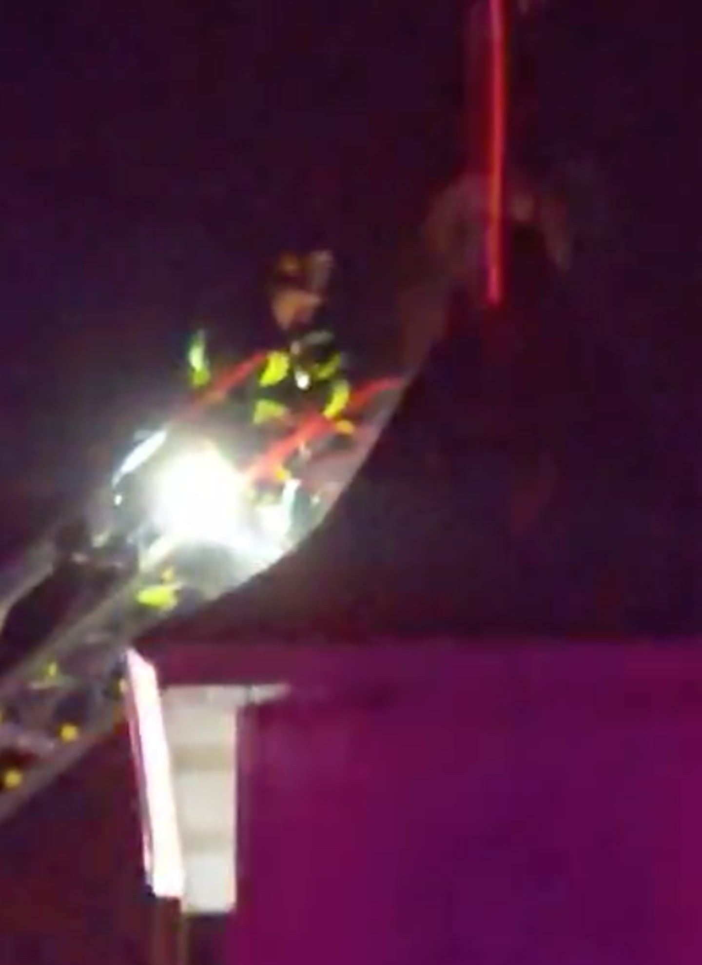 A firefighter works from atop a ladder in pouring rain and storms at St. John's Lutheran Church in Hebron the night of July 10, 2025., after a lighted cross atop the church was believed to have been struck by lightning.