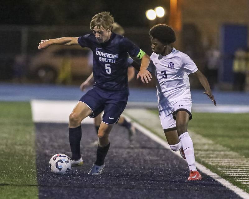Downers Grove South's Brady Dunlap (5) fends off the defense of Downers Grove North's Boonie Ford (3) during soccer match between Downers Grove North at Downers Grove South. Oct 2, 2025.