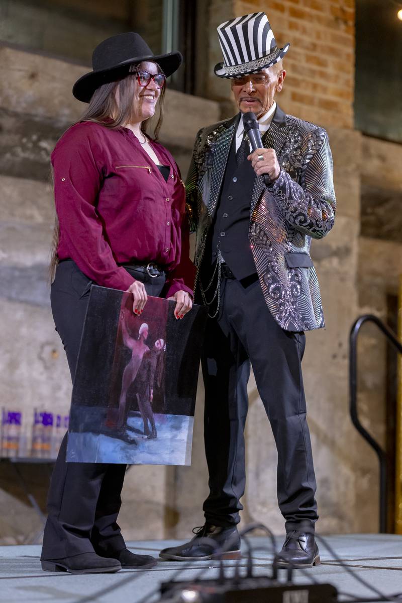 Jasmine Arce of LaSalle Peru High School presents one of her paintings to the audience at the Mad Hatter Ball on January 17, 2024 at the Westclox Event Center.