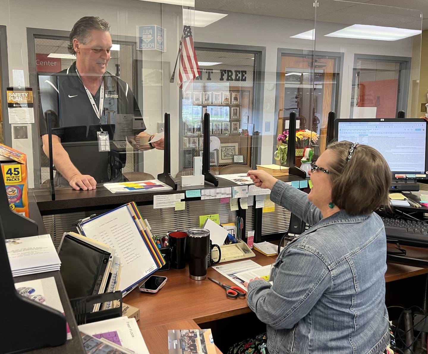 Sycamore High School Receptionist Heidi Phelps hands Sycamore High School Principal Tim Carlson a note after he returned from a meeting on April 14, 2023.