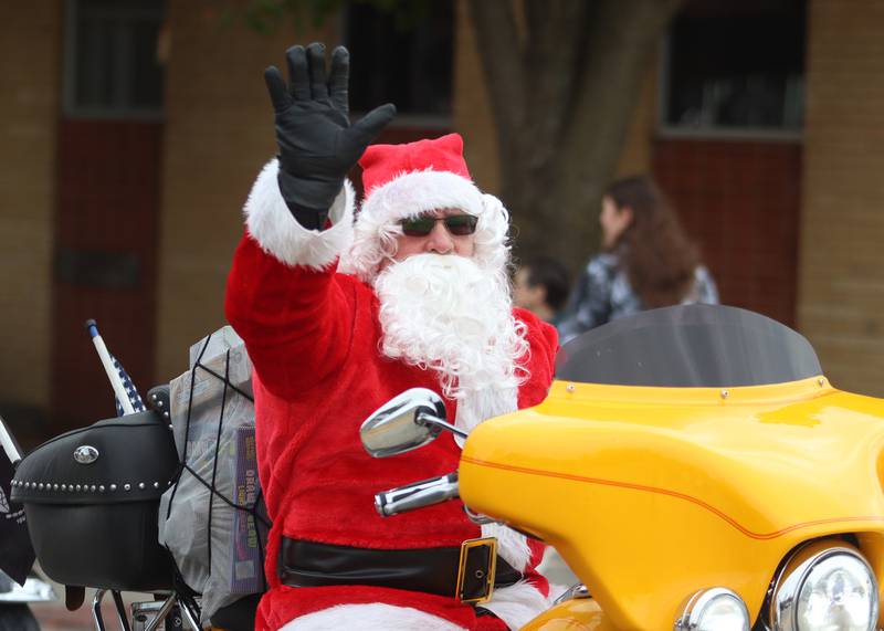 A Santa-suit clad motorcyclist greets people during the Toys for Tots Parade on Sunday, Nov. 24, 2024, in downtown McHenry.