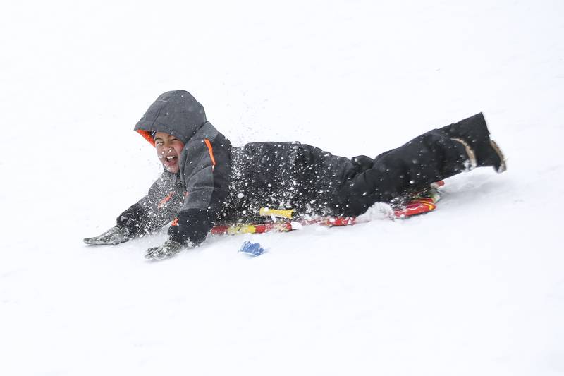 Nehemiah Dawson slides down the hill on Sunday, Jan. 31, 2021, at Cene's Four Seasons Park in Shorewood, Ill.  Nearly a foot of snow covered Will County overnight, resulting in fun for some and challenges for others.