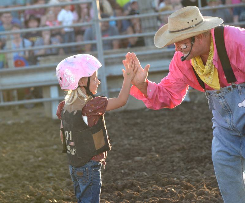 Westlyn Huss, 6, of Lee, gets a high five from the rodeo clown after competing  in the "Mutton Buster' event during the rodeo at the Lee County Fair on Saturday, July 29, 2023.