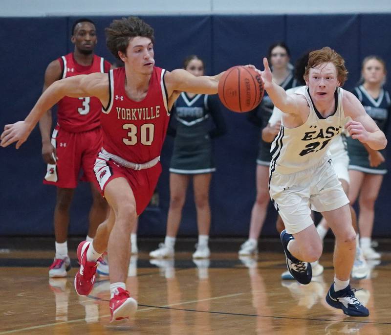 Yorkville's Bryce Salek (30) and Oswego East's Andrew Pohlman (21) chase down a loose ball during a basketball game at Oswego East High School on Friday, Dec 8, 2023.