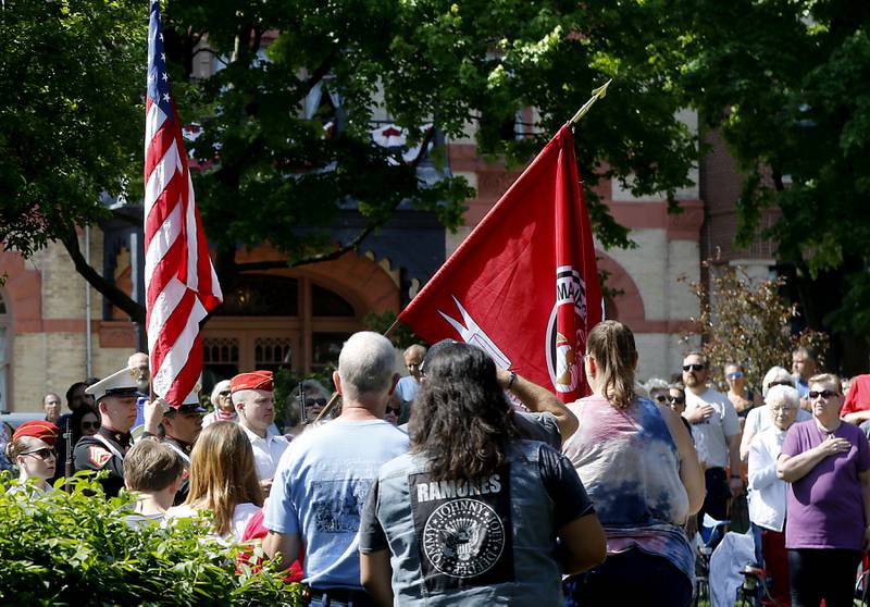 People surround the American Flag as the National Anthem is performed by a quartet from Woodstock High School during the Woodstock VFW Post 5040 City Square Memorial Day Ceremony and Parade on Monday, May 29, 2023, in Woodstock.