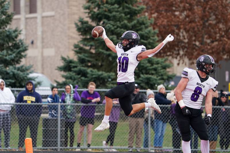 Downers Grove North's Oliver Thulin (10) leaps into the end zone scoring a touchdown on an interception against Batavia during a class 7A quarterfinal playoff football game at Batavia High School on Saturday, Nov. 16, 2024.