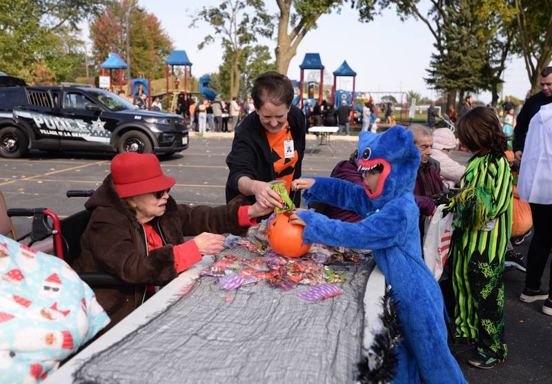 Nathan Badrov of Western Sprigs gets candy from Bethlehem Woods resident (left) Martha Lastres and Community Relations Manager Ann Reiter-Emlund on Saturday, Oct. 12, 2024 during a Trunk or Treat event at Sedgwick Park in La Grange.