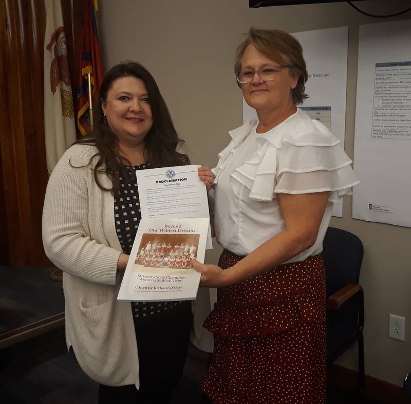 Streator Mayor Tara Bedei (left) and Alexandria "Zami" Mogill Hay hold up copies of the proclamation declaring June 10 as Champions Day in Streator and the book "Beyond Their Wildest Dreams" at the Wednesday, May 17, 2023, Streator City Council meeting.