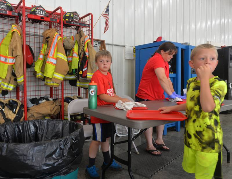Easton Lawson, 6, and Tate Hagemann, 8, and Tate's mom, Lindsey, made sure the trays were cleaned and washed down during the German Valley Fire Department's pork chop dinner on Saturday, July 15, 2023 during German Valley Days.