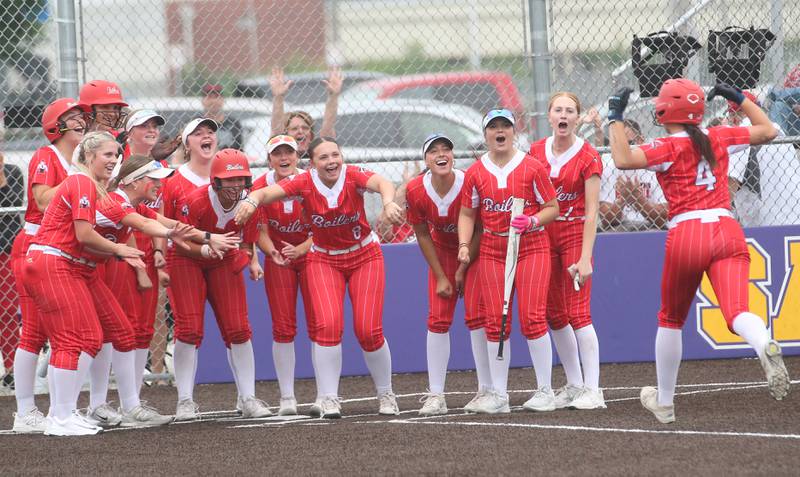 Members of the Bradley-Bourbonnais softball team stand around home plate to greet  teammate Suttyn Hop after she hit a home run during the Class 4A Supersectional game on Friday, June 6, 2025 at Monticello High School.