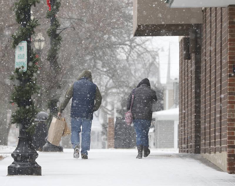 Holiday shoppers walk along Brink Street in downtown Crystal Lake as the snow falls Thursday, Dec. 22, 2022, as a winter storm hits northern Illinois.