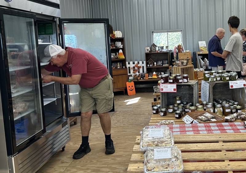 Jeff Warren, owner of  BerryView Orchard, 7504 W. Midtown Road, Mt. Morris, reaches into a freezer as he waits on a customer Saturday, Sept. 27, 2025, during the sixth annual Back Roads Market.