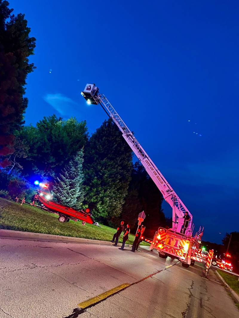 DeKalb firefighters are hoisted into the air on a ladder truck to help provide light to emergency divers undertaking a water rescue on Sunday, July 27, 2025, in the 600 block of Ridge Drive in DeKalb.