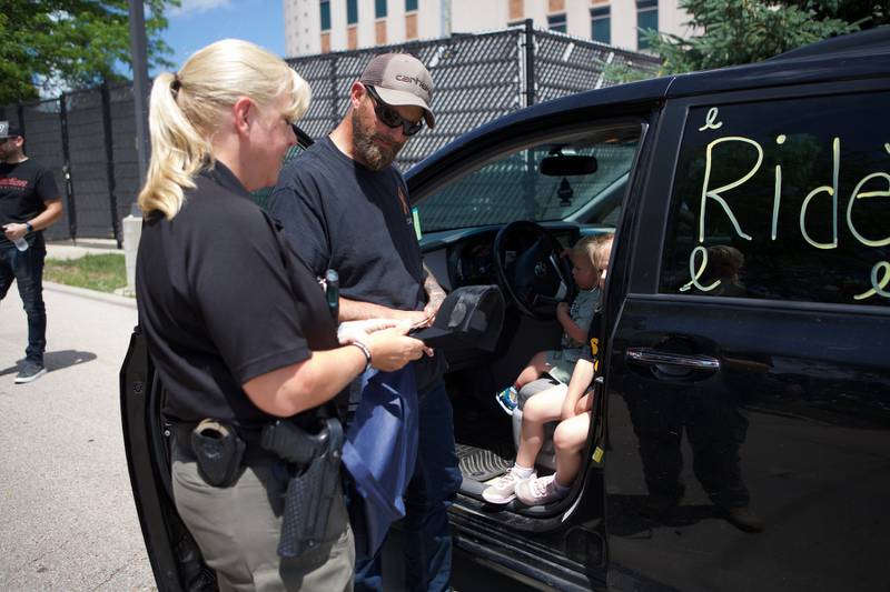 Oilver Olinger and Nathan Olinger get gifts from Kane County Sheriff Sue Deuchler outside Sycamore Library for a Ride for Oliver on Sunday, June 22, 2025 in Sycamore. "Rally for Oliver," was meant to support Oliver as he was escorted by first responders to the St. Charles Motorcycle Museum to celebrate his cancer remission.