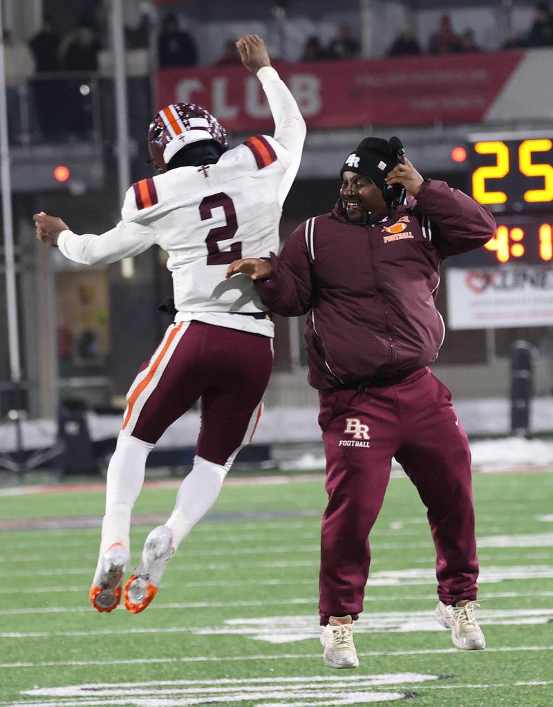 Brother Rice's C.J. Gray and an assistant coach celebrate as time ticks away Wednesday, Dec. 3, 2025, during their IHSA Class 7A state chamionship win over St. Rita in Huskie Stadium at Northern Illinois University in DeKalb.