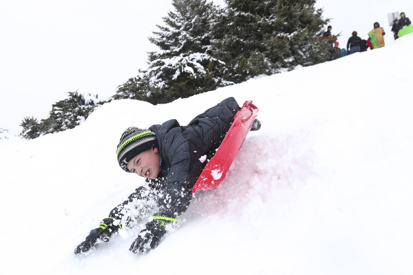 A sledder wipes out after hitting a jump on Sunday, Jan. 31, 2021, at Cene's Four Seasons Park in Shorewood, Ill. Nearly a foot of snow covered Will County overnight, resulting in fun for some and challenges for others.